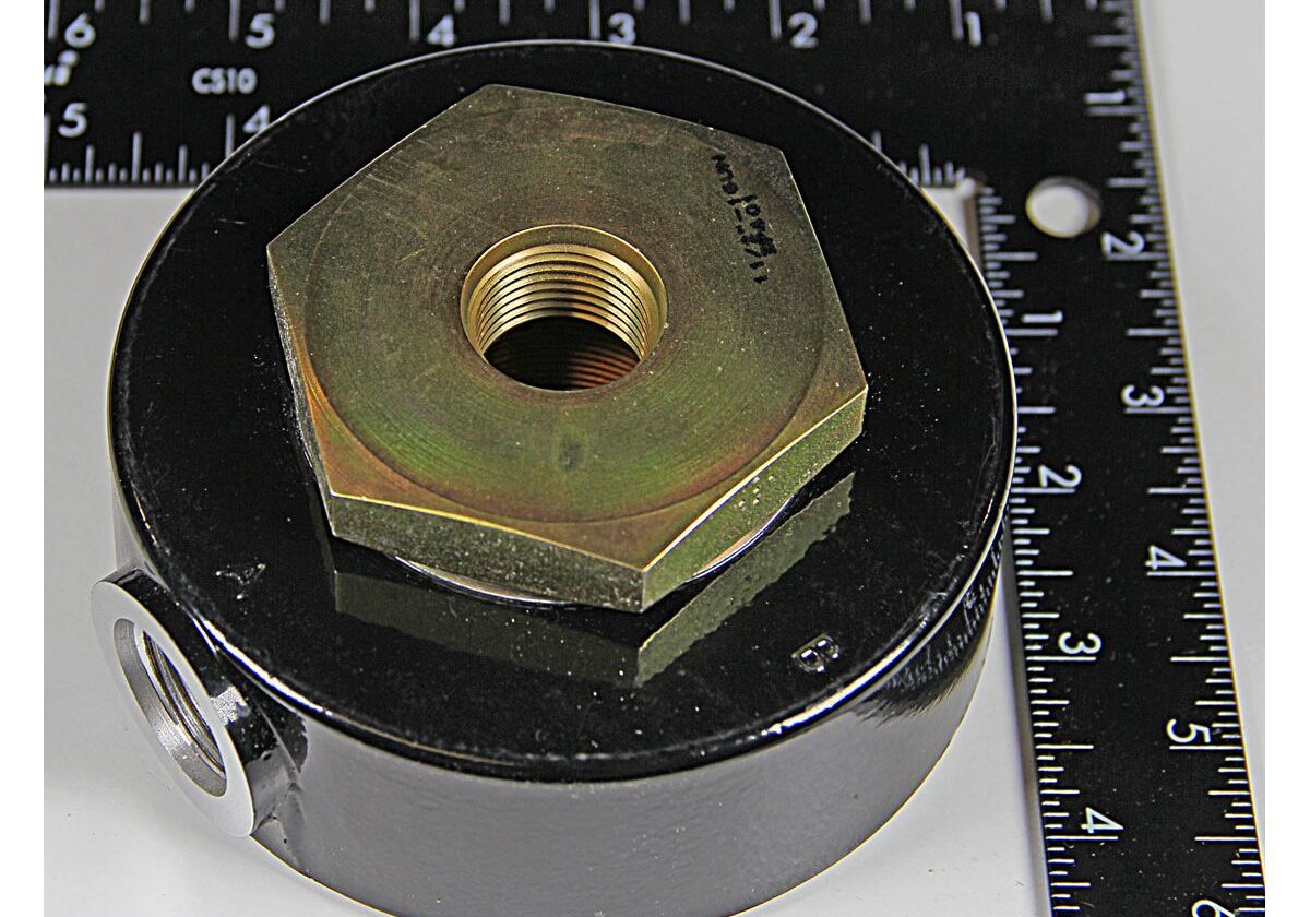 Metal component next to a measuring ruler.