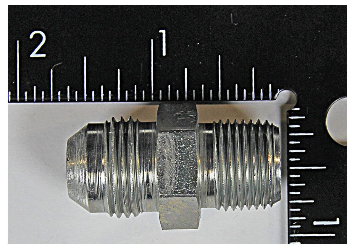 Metal fitting with measuring ruler background.