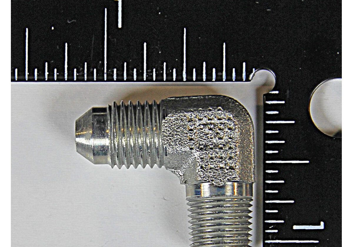Metal elbow pipe fitting with ruler scale.
