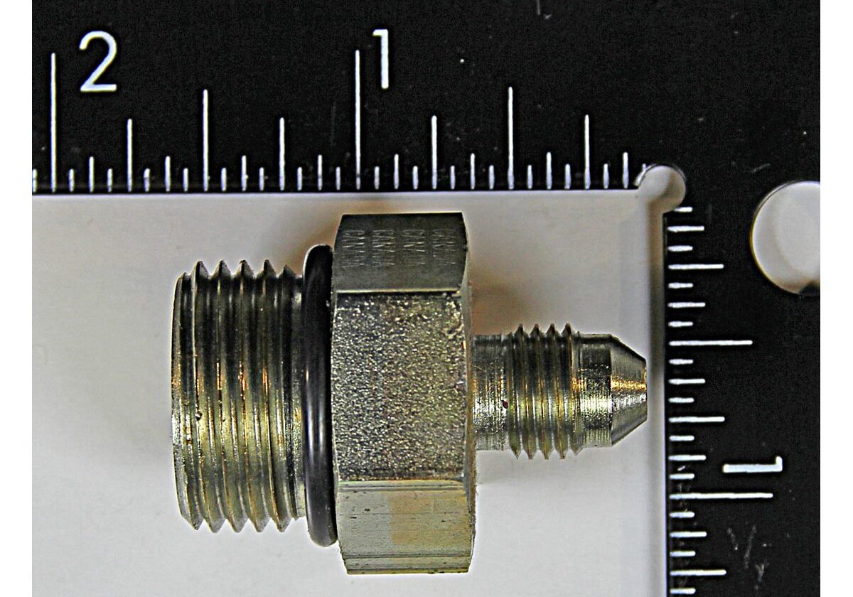 Metal pipe fitting with measurement scale background.